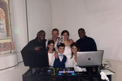 Un groupe de personnes, incluant des enfants et des adultes, posant devant une table de mixage avec des ordinateurs.