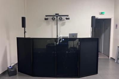 Installation de matériel de sonorisation et éclairage avec une table de mixage et des enceintes dans une salle.