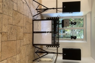 Installation de matériel de sonorisation avec deux enceintes sur pieds et une table de mixage dans une pièce lumineuse.