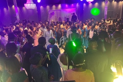 Groupe de personnes dansant et célébrant dans une salle éclairée par des lumières colorées et des lustres.