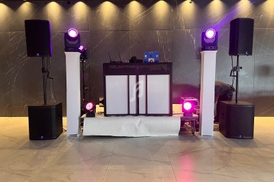 Installation de matériel de sonorisation et d'éclairage avec une table de mixage et des projecteurs violets allumés.