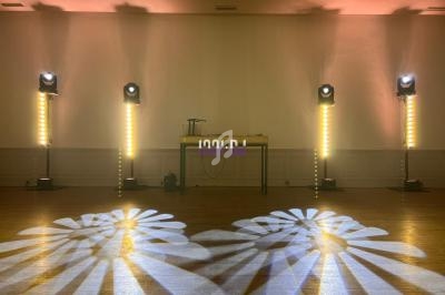 Jeu de lumières projetant des motifs au sol dans une salle avec un mur blanc et une table équipée d'appareils.