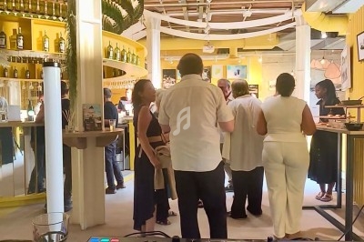 Vue d'une salle animée avec des personnes debout près d'un bar, en arrière-plan d'une table de mixage de DJ.