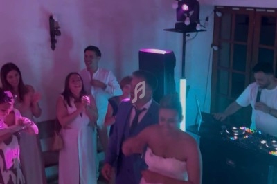 Un couple danse entouré d'invités dans une ambiance festive avec un DJ et des lumières colorées.