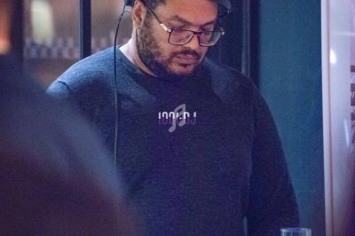 Un homme portant un casque audio se tient concentré devant un équipement dans un environnement intérieur sombre.