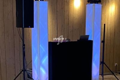 Installation de matériel de sonorisation et d'éclairage dans une salle avec murs en bois et parquet clair.