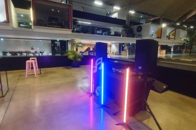 Poste de DJ avec éclairage LED coloré dans un espace moderne et ouvert, entouré de mobilier et de baies vitrées.