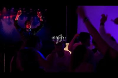Un DJ anime une soirée dansante avec des lumières colorées et un public en mouvement.