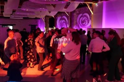 Personnes dansant lors d'une soirée festive dans une salle éclairée par des lumières colorées.