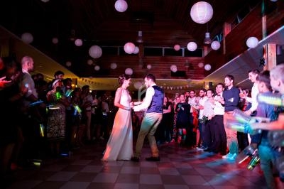 Un couple danse au centre d'une salle décorée de lanternes, entouré d'invités applaudissant.