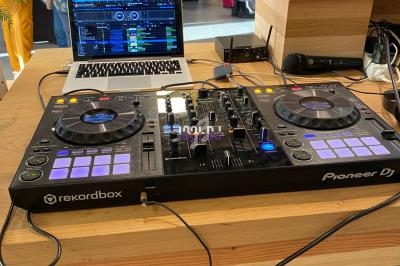 Console DJ Pioneer avec ordinateur portable affichant un logiciel de mixage, installée sur une table lors d'un événement.