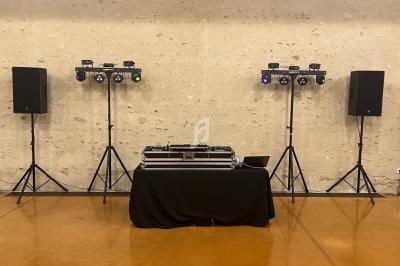 Équipement de sonorisation et éclairage installé dans une salle, avec une table recouverte d'une nappe noire au centre.