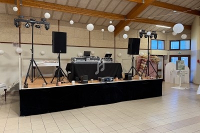 Scène équipée de matériel de sonorisation et d'éclairage dans une salle avec décoration festive suspendue.