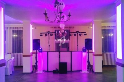 Salle de réception avec éclairage violet, piste de danse et équipement sonore installé sous un lustre central.