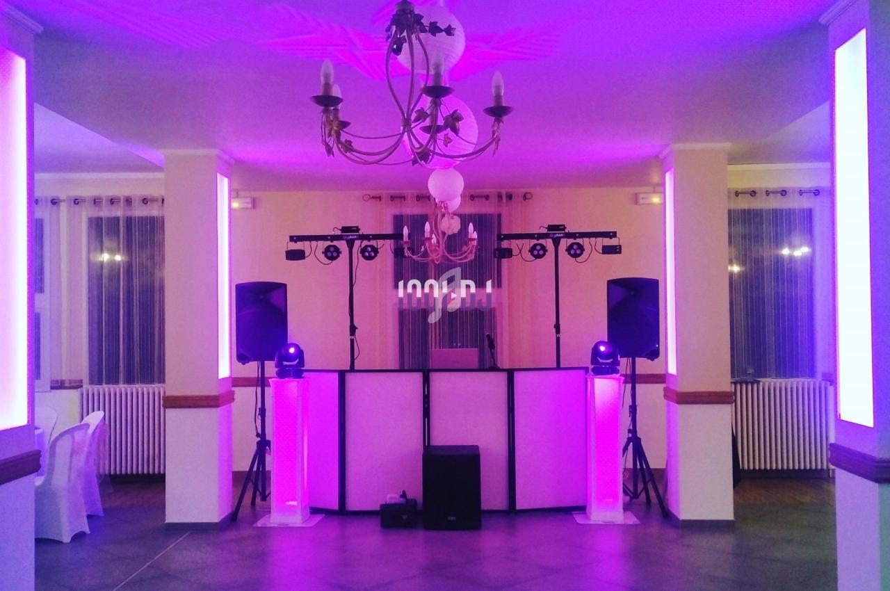 Salle de réception avec éclairage violet, piste de danse et équipement sonore installé sous un lustre central.