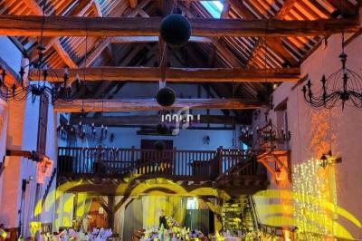 Salle de réception avec charpente en bois apparente, tables dressées et éclairage chaleureux.