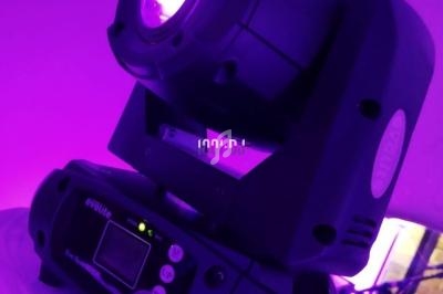 Projecteur LED motorisé émettant une lumière violette dans un environnement sombre.