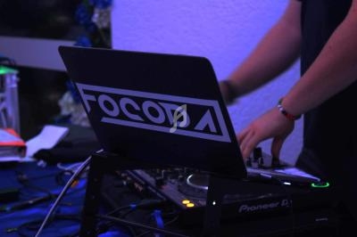 Un DJ mixe de la musique sur une console avec un ordinateur portable affichant un logo.