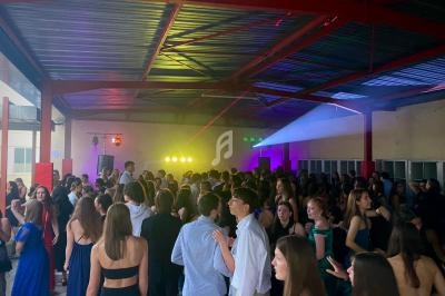 Groupe de jeunes dans une salle couverte, éclairée par des lumières colorées, participant à une fête ou un événement.