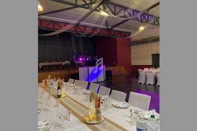 Salle de réception décorée avec des tables dressées, un éclairage coloré et une piste de danse en arrière-plan.