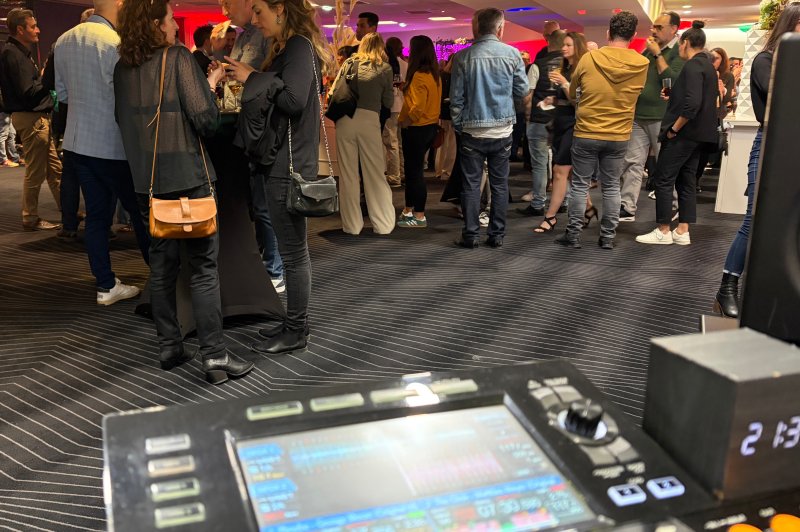 Vue d'une soirée avec des invités discutant debout, un équipement de DJ visible au premier plan.