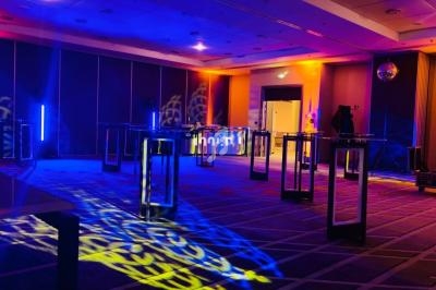 Salle de réception avec éclairage coloré, tables hautes et motifs lumineux projetés au sol.