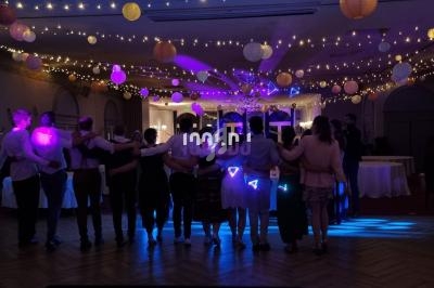 Groupe de personnes alignées, de dos, dans une salle décorée de guirlandes lumineuses et lanternes suspendues.