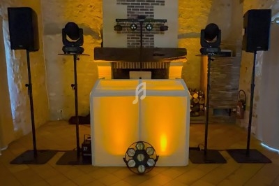 Installation de matériel de sonorisation et d'éclairage avec une table de mixage illuminée dans une salle en pierre.
