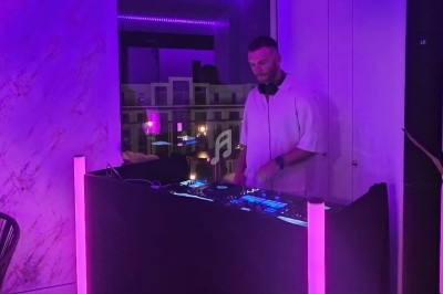 Un DJ mixe de la musique sur une table de mixage dans une pièce éclairée par des lumières violettes.