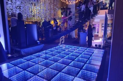 Piste de danse lumineuse à LED avec des invités debout et montant un escalier dans un espace événementiel.