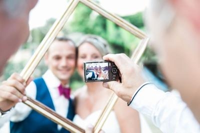 Un couple souriant est encadré par un cadre doré, photographié de près avec un appareil photo compact.