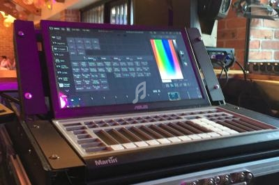 Console de contrôle d'éclairage avec écran tactile affichant des paramètres colorimétriques, installée dans un espace…