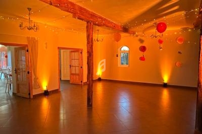 Salle spacieuse avec éclairage chaleureux, poutres en bois, lanternes suspendues et fenêtres en arc.