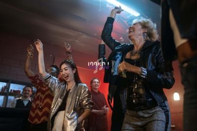 Des personnes dansent et sourient dans une ambiance festive avec éclairage tamisé.