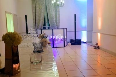 Salle de réception décorée avec des lumières colorées, une table avec des fleurs et une tour de verres.