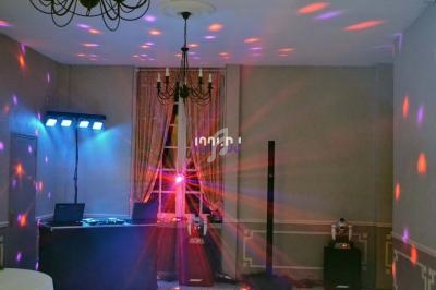 Salle avec éclairage coloré, matériel de sonorisation et jeux de lumière installés pour un événement festif.