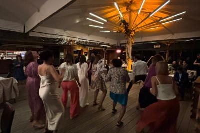 Des personnes dansent en groupe sous une tente éclairée par des lumières chaudes, sur un sol en bois.