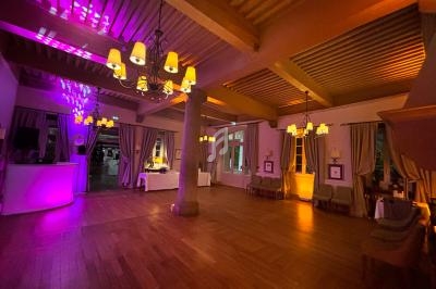 Salle de réception chaleureuse avec parquet en bois, éclairage tamisé et lustres suspendus.