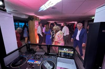Vue depuis une table de mixage sur des personnes dansant dans une salle éclairée par des lumières colorées.