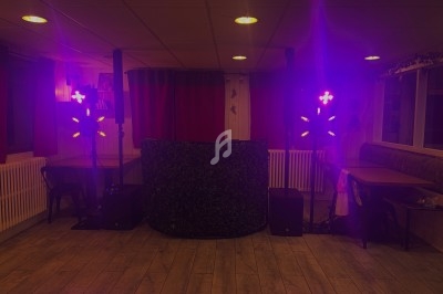 Installation lumineuse violette avec des projecteurs LED entourant une table recouverte de feuillage dans une salle.