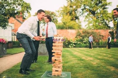 Un groupe de personnes joue à un jeu de blocs en bois dans un jardin lors d'une journée ensoleillée.