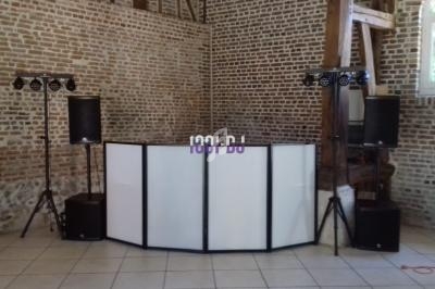 Console de DJ avec éclairage et enceintes installée dans une salle aux murs en briques apparentes.