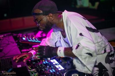 Un DJ mixant sur une table de mixage dans un environnement sombre avec des lumières colorées.