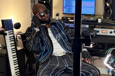 Un artiste en studio d'enregistrement, assis avec un casque audio, entouré d'équipements musicaux.