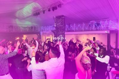 Groupe de personnes dansant et célébrant dans une salle éclairée par des lumières colorées.