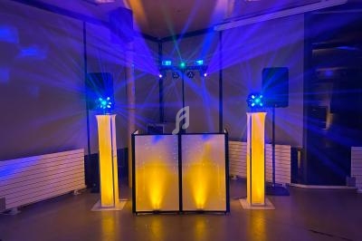 Installation de matériel de sonorisation et d'éclairage avec jeux de lumières colorées dans une salle sombre.