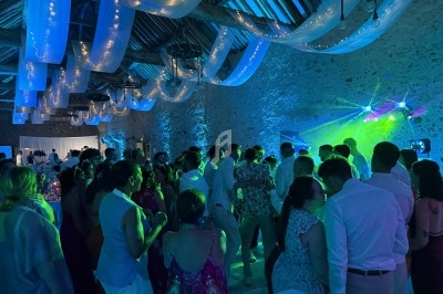 Groupe de personnes dans une salle en pierre éclairée par des lumières colorées, lors d'une fête ou d'un événement.