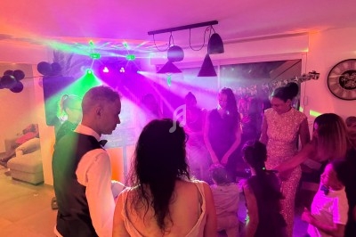 Personnes dansant et discutant sous des lumières colorées dans une ambiance festive en intérieur.