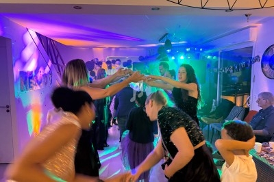 Des personnes dansent sous des lumières colorées lors d'une fête dans une salle décorée.