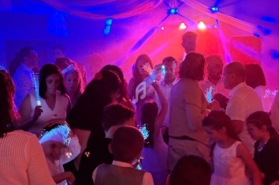 Groupe de personnes dansant sous des lumières colorées dans une ambiance festive en intérieur.